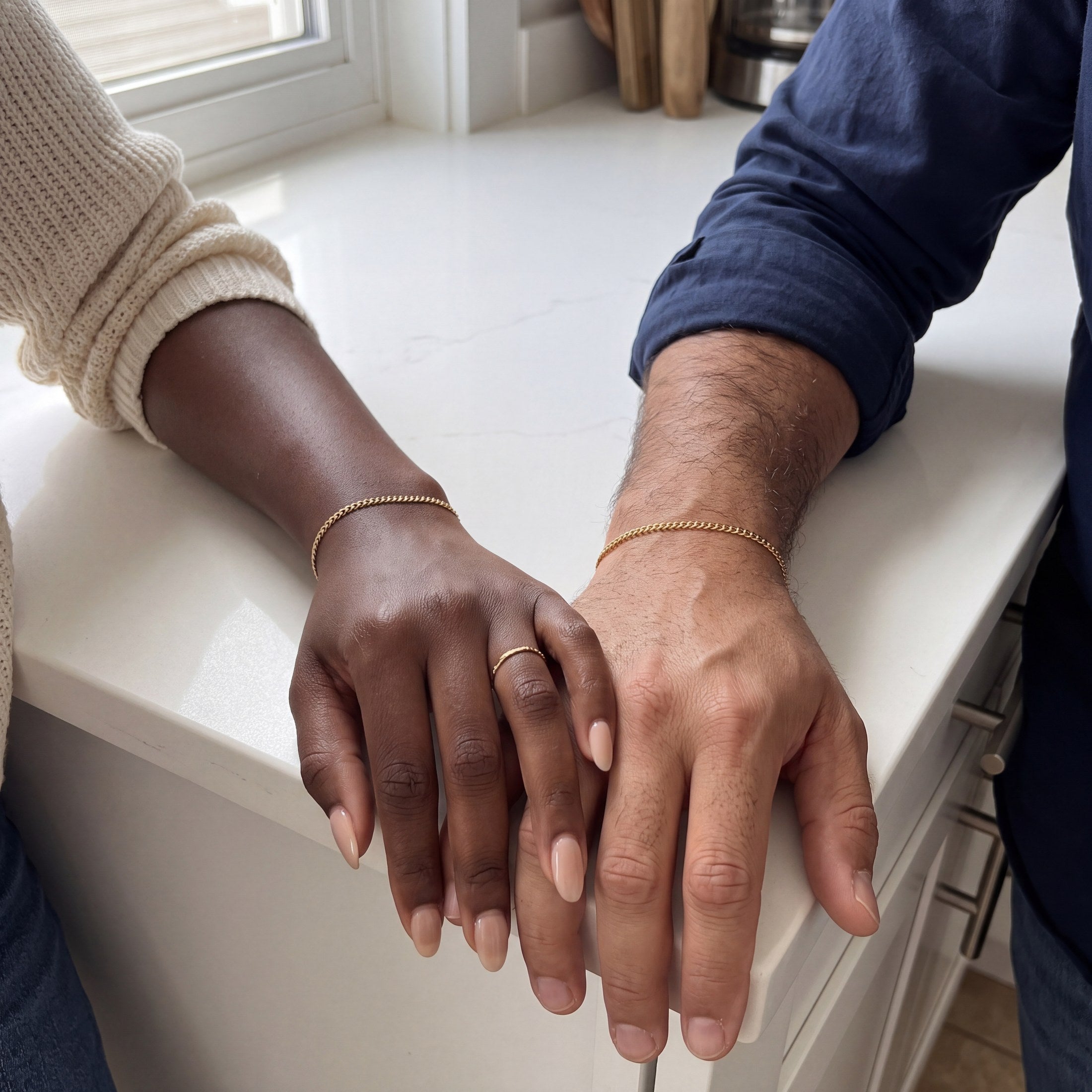 Two wrists wearing the matching gold bracelets