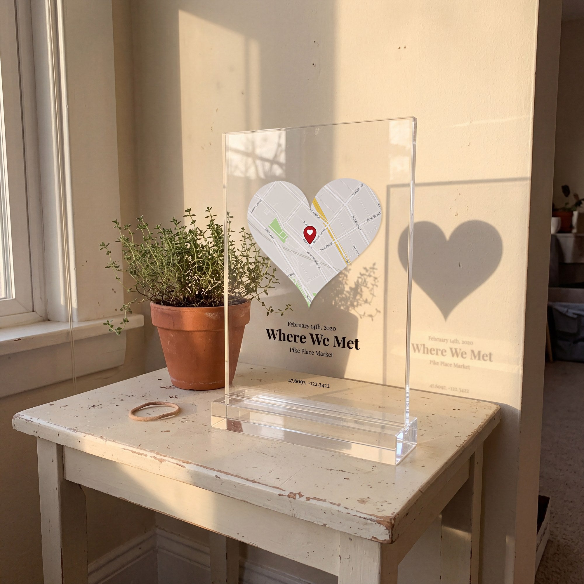 Clear heart map plaque of Pike Place Market in a clear stand, lit by low morning sun beside a window